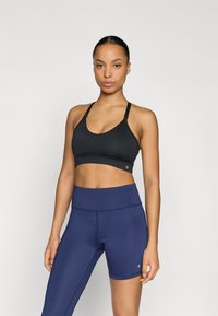 Czarny sportowy biustonosz z dekoltem w kształcie litery U, regulowanymi ramiączkami i gładką fakturą, zestawiony z granatowymi wysokim stanem szortami z płaskim szwem.