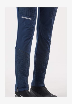 Navy athletic pants with a quilted texture on lower sides, featuring an ankle zipper. Made of stretchy material with a streamlined fit.