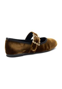 Scarpa piatta in velluto marrone con punta rotonda, rifinitura elastica nera e una fibbia decorativa. Suola piatta, texture liscia.