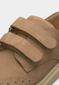 Ανοιχτό καφέ παπούτσι από σουέντ με δύο φαρδιές λωρίδες με βέλκρο και λεπτομερείς ραφές στο πάνω μέρος.