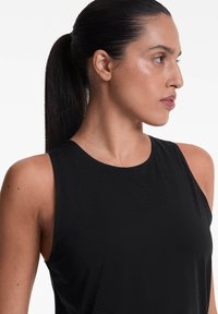 Sort atletisk tanktop med ærmeløst design, glat tekstur, subtile perforerede detaljer foran og rund halsudskæring.