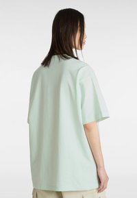Mintgrünes, übergroßes Baumwoll-T-Shirt mit kurzen Ärmeln und Rundhalsausschnitt. Die Rückseite weist eine glatte, schlichte Oberfläche auf.