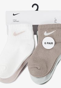 Pachet de șosete Nike până la gleznă, șase perechi: trei albe, trei în bej și bleu deschis, cu textură nervurată și logo mic pe fiecare șosetă.