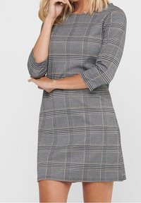 Robe à carreaux gris avec une coupe ajustée, des manches trois-quarts et un col rond. Le motif à carreaux présente des largeurs et des couleurs variées.