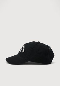Svart baseballcap med hvit brodert tekst på forsiden som leser "JEANS" vist på en enkel hvit bakgrunn.