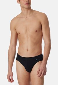Schwarze Baumwollslips mit solidem Design, elastischem Bund und subtilen Logodetails. Sanfte Textur und figurbetonte Form für hohen Tragekomfort.