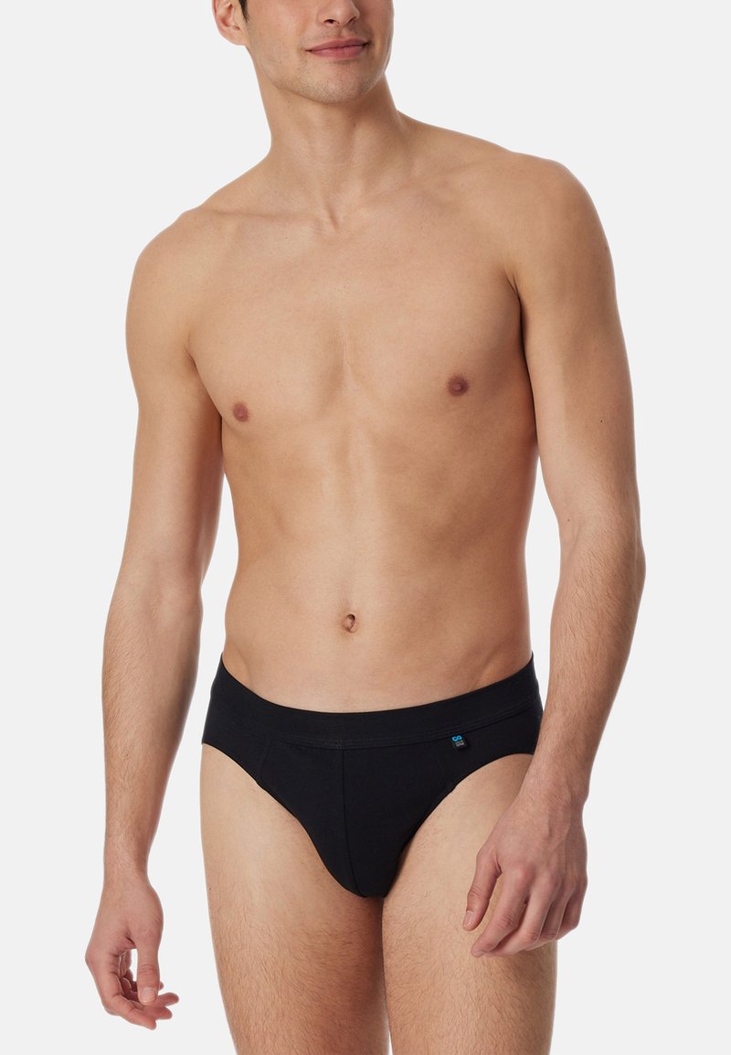 Schwarze Baumwollslips mit solidem Design, elastischem Bund und subtilen Logodetails. Sanfte Textur und figurbetonte Form für hohen Tragekomfort.