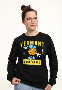 Felpa nera con un personaggio a cartone di basket in cappello, testo "VERMONT BASKETBALL" in giallo e dettagli blu. Taglio casual.