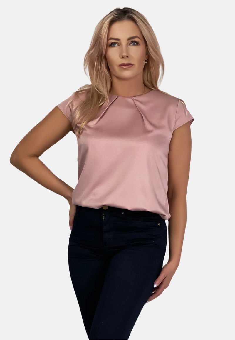 Bluzka z krótkim rękawem w pastelowym różu, z plisowanym dekoltem. Noszona z ciemnymi dżinsami. Gładka tekstura, swobodny krój, minimalistyczny design.