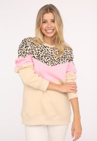 Sweatshirt à col rond avec un imprimé léopard, des blocs de couleurs rose et beige. Matériau doux avec des poignets et une taille côtelés.