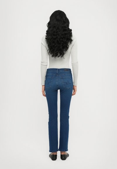 Strakke jeans in donkerblauwe denim met een gladde textuur, voorzien van achterzakken en een aansluitende pasvorm. Lange mouwen grijs shirt.