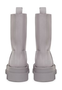 Botas de tobillo de imitación cuero gris con suela gruesa, que presentan costuras prominentes y tiradores en la parte posterior para ponerlas y quitarlas fácilmente.