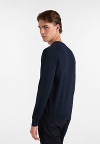Suéter de manga larga azul marino en suave tejido de punto con puños y dobladillo acanalados, con cuello redondo y un diseño ajustado.
