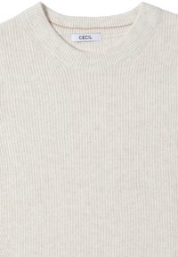 Hellbeige gerippter Strickpullover mit klassischem Rundhalsausschnitt und einem Label mit der Aufschrift "CECIL" am Kragen. Weiche Textur im gesamten Pullover.