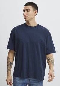 Navy blue cotton t-shirt with a loose fit, round neckline, short sleeves, and a small logo detail on the chest.