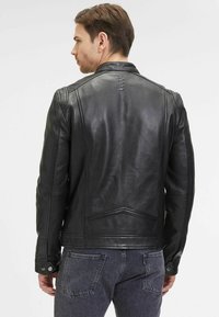 Giacca da motociclista in pelle nera con design classico, caratterizzata da un colletto ribaltabile, dettagli con cuciture verticali e polsini con chiusura a scatto.