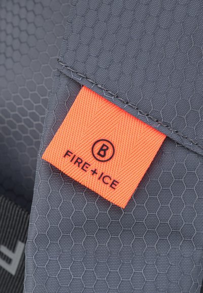 Tessuto grigio testurizzato con un motivo esagonale, caratterizzato da un'etichetta arancione che riporta la scritta "FIRE+ICE" in lettere nere.