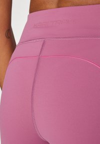 Pink hohe Leggings aus glattem, dehnbarem Material mit einem flachen Nahtdesign und Logodetail am Bund.