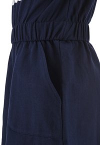 Vestito blu navy con vita elastica e tasche laterali, realizzato in tessuto morbido con una texture liscia, mostrato di lato.