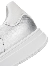 Nærbillede af hælen på en sølv- og hvid sneaker med struktureret læder og en tyk hvid gummisål.