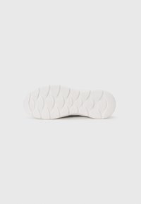 Semelle de sneaker blanche avec des motifs ondulés texturés et des rainures pour une meilleure traction, présentant un design lisse et épuré avec des bords arrondis.