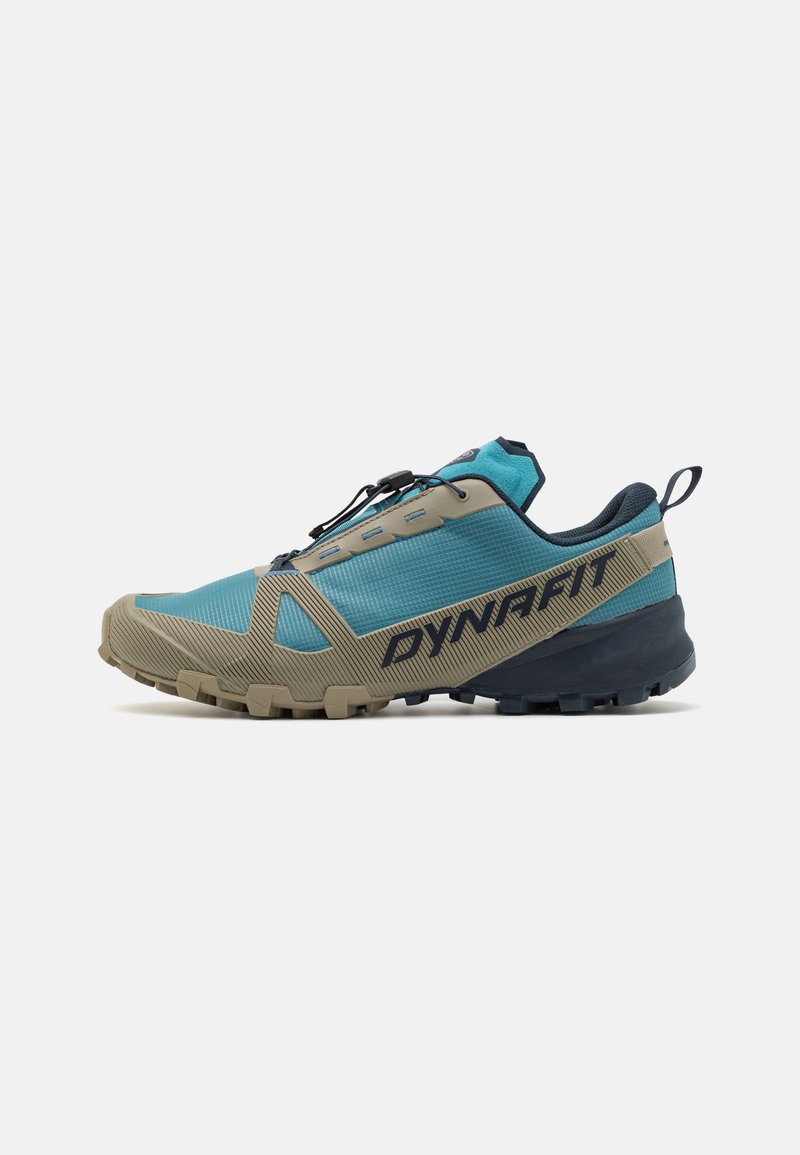 Sapato de corrida de trilho com um upper de malha azul e bege, fecho de laço, e sola de borracha texturizada para aderência. Apresenta a marca "DYNAFIT".