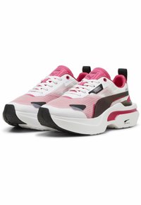 Białe i różowe buty sportowe z siateczkową i syntetyczną cholewą. Charakteryzują się sznurowanym zapięciem, wyraźnymi czarnymi akcentami i grubą gumową podeszwą.