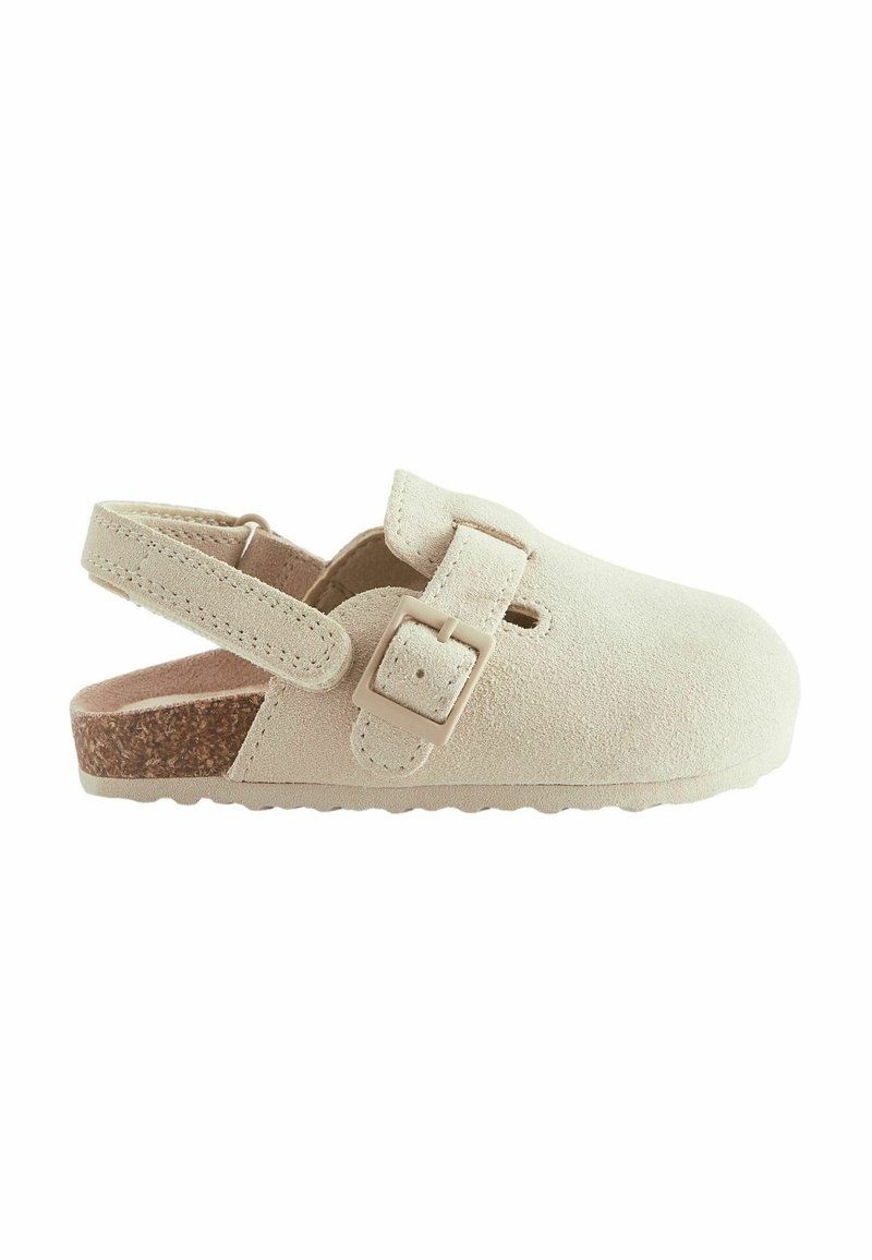Sandale beige en daim à bout fermé avec bride à boucle réglable et semelle en liège, conçue pour le confort et un usage décontracté.