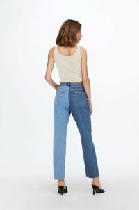 Light beige tank top paired with high-waisted blue denim jeans featuring a gradient wash, straight legs, and two back pockets.