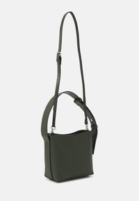 Sac à bandoulière rectangulaire en cuir vert foncé avec deux bretelles réglables, une large et une étroite, boucles en métal argenté sur fond uni.