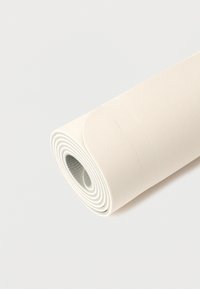 Tapis de yoga beige clair enroulé avec surface texturée sur un fond blanc uni.