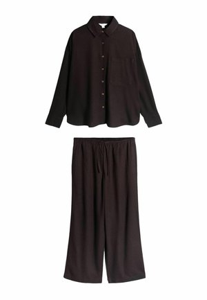 Fekete hosszú ujjú, gombolós ing gallérral és mellzsebbel, fekete, bő szárú, húzózsinóros nadrággal párosítva.