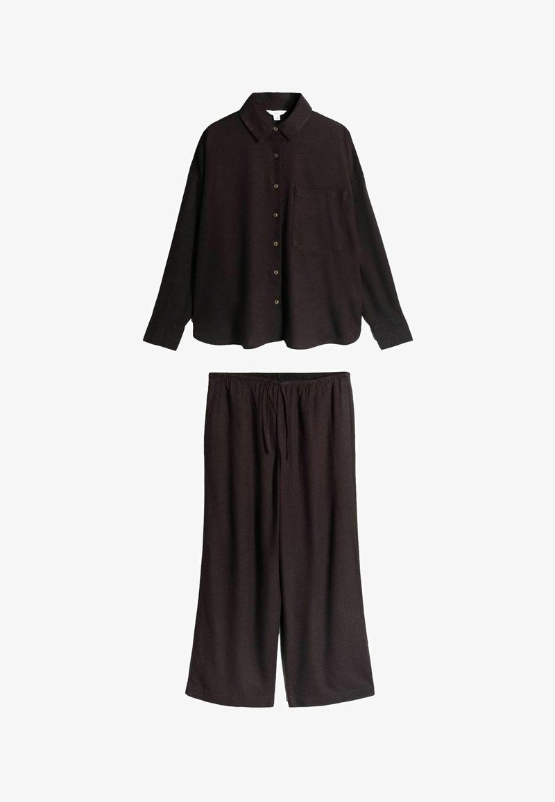 Zwarte blouse met lange mouwen, knopen, kraag en borstzak, gecombineerd met zwarte, wijde broek met trekkoord.