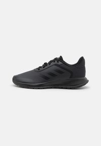 Scarpe sportive nere con una parte superiore testurizzata, caratterizzate da tre strisce nere sul lato, una suola imbottita e un design a punta arrotondata.