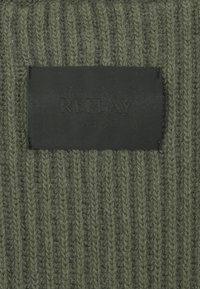 Olivgrüner Strickstoff mit vertikaler Rippstruktur, versehen mit einem schwarzen Lederetikett, das mit "REPLAY" und "SINCE 1981" geprägt ist.
