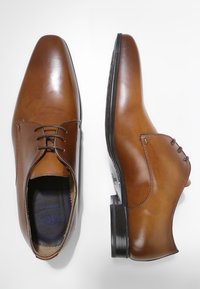 Chaussures de ville en cuir marron avec une finition lisse, bouts pointus, lacets à l'avant et détails de couture subtils. Semelles en caoutchouc avec un léger talon.