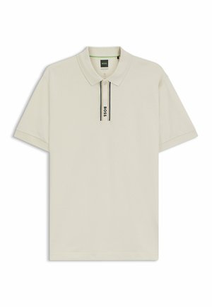 Camisa polo en beige claro, con un cuello clásico, mangas cortas y una abertura con cremallera adornada con una franja negra contrastante y un logo.