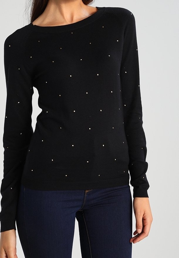 Svart stickad tröja med långa ärmar och lös passform, prydd med gyllene prickar som är jämnt fördelade över framsidan.
