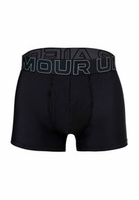 Svarta boxertrosor tillverkade av ett mjukt tyg med ett tjockt elastiskt midjeband som har varumärket tryckt i kontrasterande grått. Sömmen är synlig.