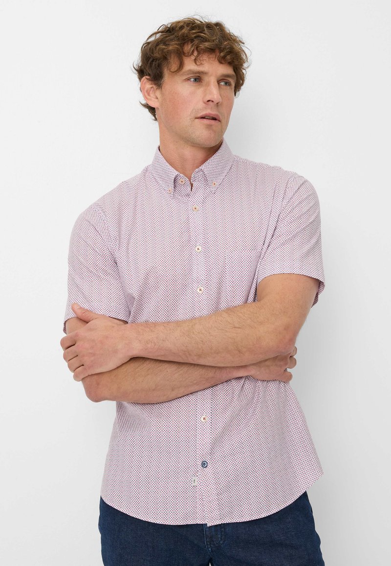Camicia a maniche corte con bottoni di colore rosa chiaro, caratterizzata da un motivo geometrico, colletto classico, bottoni a contrasto e taschino.