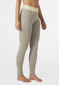 Lichtbeige leggings met een textuurafwerking, voorzien van limoen gele stiksels en accenten, en een logo tailleband. Strakke pasvorm, enkel lengte.