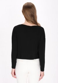 Schwarz, langärmliges Oberteil mit weitem Rundhalsausschnitt und abgesenkten Schultern; aus einem glatten, leichten Material; cropped Design.