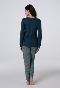 Maglietta azzurra a maniche lunghe e pantaloni a stampa leopardo. La maglietta presenta un colletto rotondo; i pantaloni hanno una vestibilità aderente e una vita elasticizzata. Texture liscia.