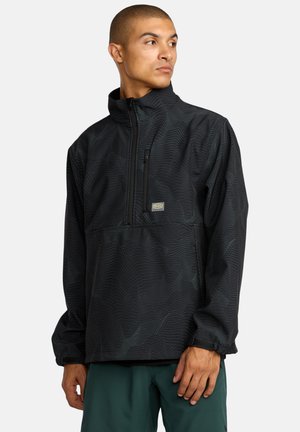 Schwarze Pulloverjacke mit strukturiertem Wellenmuster, halbseitigem Reißverschluss und verstellbaren Bündchen. Verfügt über eine Fronttasche mit Reißverschluss.
