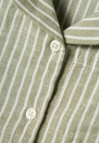 Camicia di lino con righe verticali verdi e bianche, chiusura a bottoni e una consistenza morbida con colletto a revers.