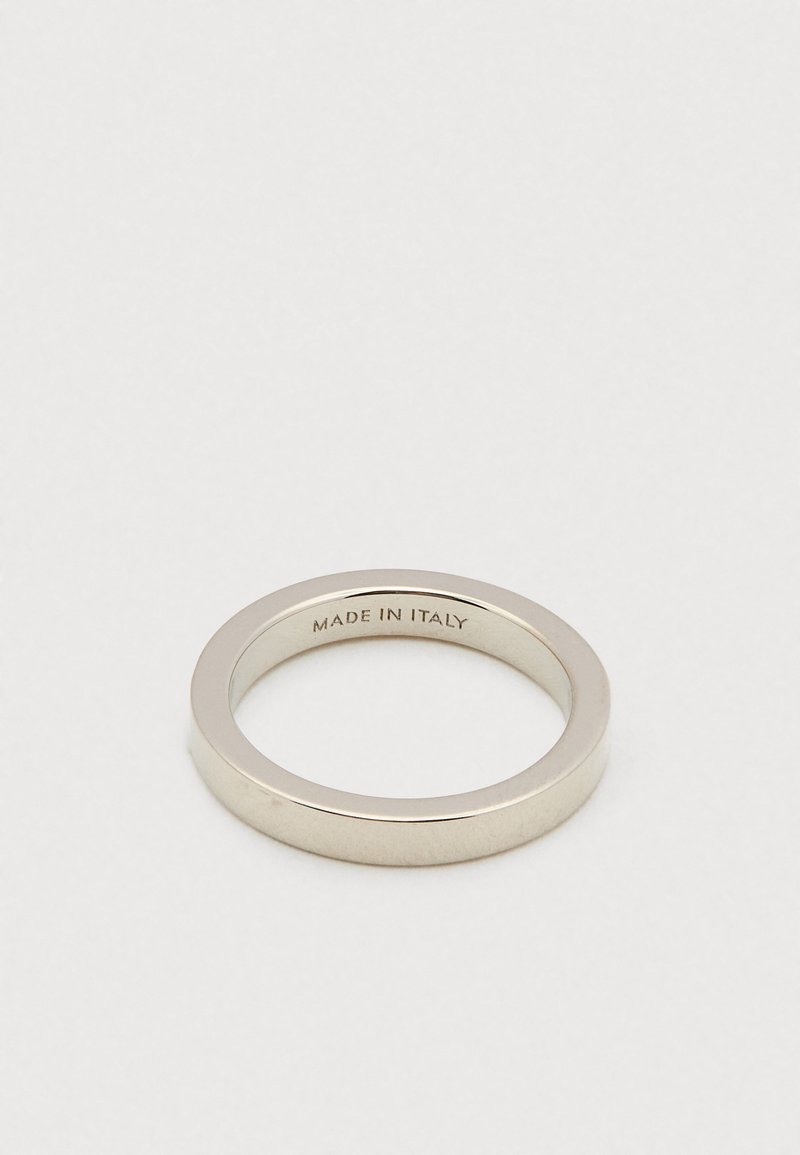En enkel silverring med "MADE IN ITALY" graverat på insidan, liggande på en vit yta.