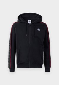 Sudadera con cremallera negra y franjas laterales rojas, capucha con cordón y logo de Kappa. Presenta patrones texturizados en las mangas y puños y dobladillo acanalados.