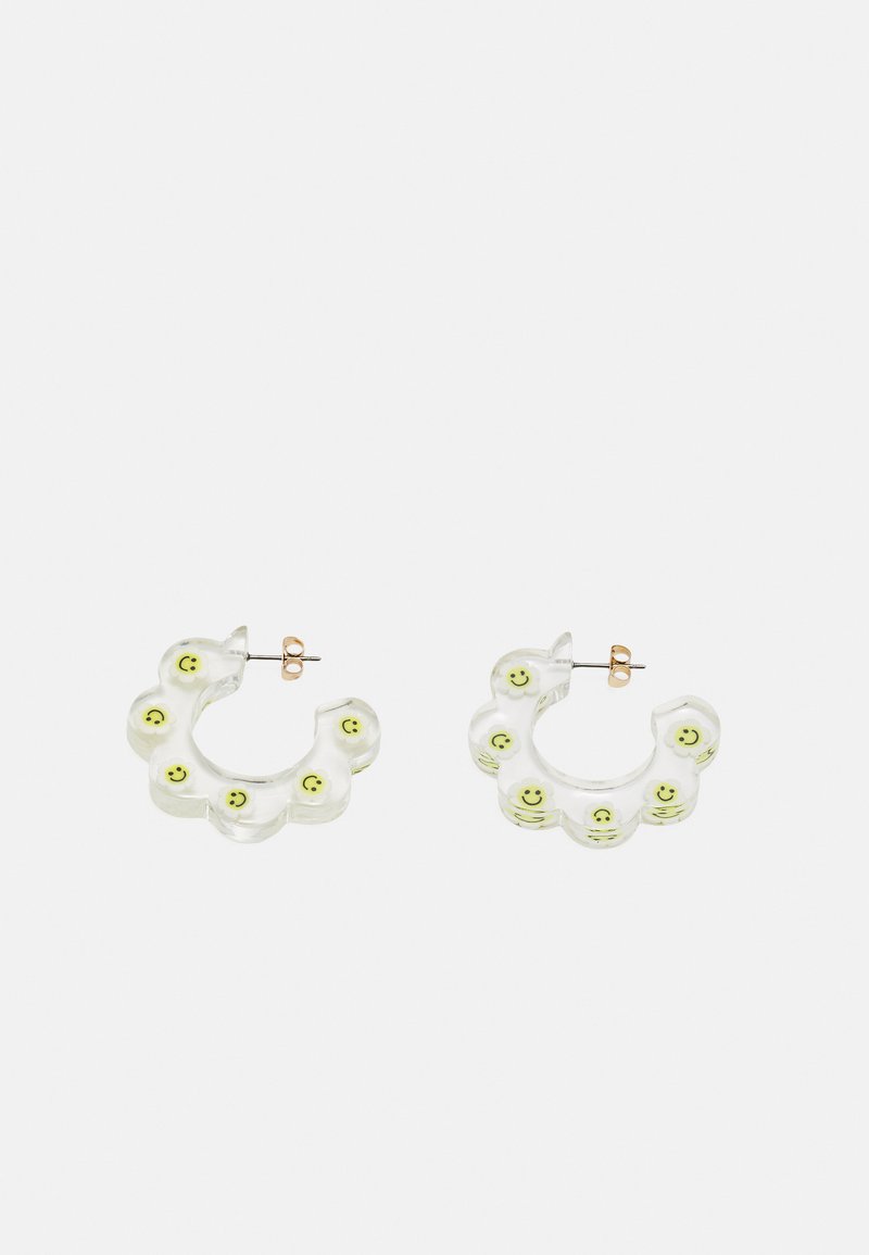 Brincos em acrílico transparente em forma de flores, apresentando rostos sorridentes verdes ao longo da borda e acabamento em metal dourado.