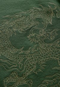 Textil verde cu un design embosat de dragon într-o nuanță mai deschisă. Textura este moale, cu detalii intricate în solzii și trăsăturile dragonului.