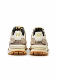 Beige mokkasiner med hvite hæltrekk, gull "F"-logoer, kraftige beige såler og "Floris van Bommel"-merke på baksiden.